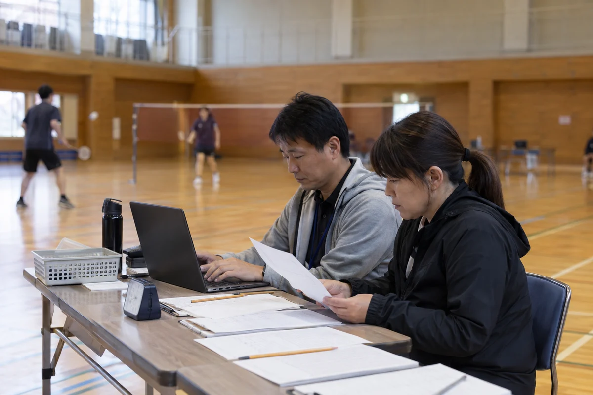 大会の進行を机で確認する運営スタッフのイメージ